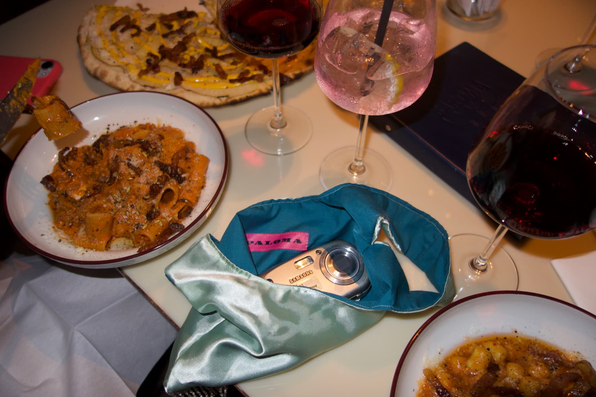 Mint PALOMA pouch open on a dinner table with pasta, flatbread and red wine